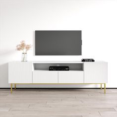 an entertainment center with a flat screen tv mounted on it's sideboard, in front of a white wall