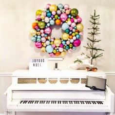 a white piano sitting in front of a christmas wreath on the side of a wall