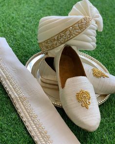 two white shoes with gold trims are sitting on the grass next to a pair of slippers