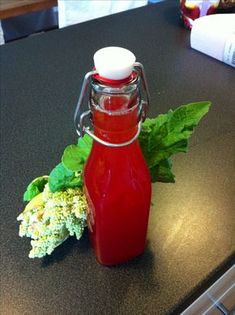 a bottle of ketchup sitting on top of a counter next to some leaves