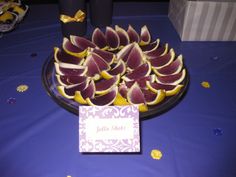 a plate full of sliced up fruit on a blue table cloth with a name tag