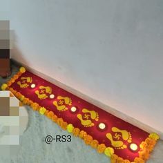 there is a decorated red and yellow table runner on the floor with candles in it