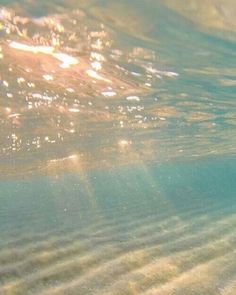 the sun shines through the water as it reflects on the sandy beach bottom surface