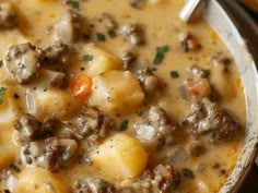 a close up of a bowl of food with meat and potatoes in it on a table