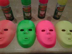 five different colored masks are lined up in a row on a counter with glue bottles