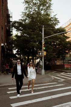 a man and woman walking across a cross walk