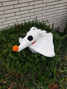 a stuffed animal laying on top of a lush green field next to a brick wall