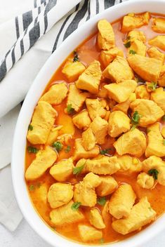 a white bowl filled with chicken curry and garnished with parsley on top