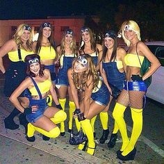 a group of women dressed in costumes posing for a photo on the street at night