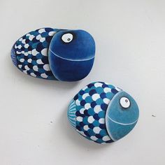 two blue and white fish shaped rocks sitting on top of a table