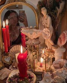 a woman taking a selfie in front of a mirror with candles and shells on it