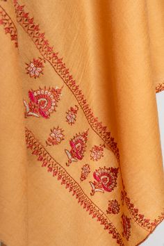 This warm golden-beige merino wool scarf is a true masterpiece, featuring stunning sozni embroidery in autumnal hues. The intricate floral patterns that run across the scarf reflect the elegance of Kashmiri craftsmanship, making it a perfect accessory for those who appreciate understated luxury. Ideal for both formal and casual occasions, this scarf offers the softness and warmth of merino wool combined with the timeless art of hand embroidery. Its versatile style ensures it can complement any w Luxury Resham Embroidery Shawl Scarf, Elegant Beige Embroidered Scarves, Elegant Beige Embroidered Scarf, Embroidered Multicolor Shawl Scarf, Sozni Embroidery, Red Embroidered Shawl Scarf, Embroidered Orange, Embroidered Rug, Scarf Jacket