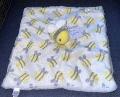 a yellow and gray bee on a white blanket with tags attached to the back of it