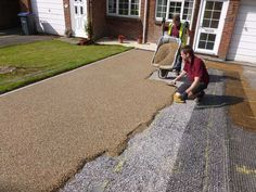 a man sitting on top of a driveway next to a pile of gravel near a house