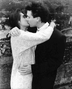 black and white photograph of a couple kissing on a bridge over looking the city below