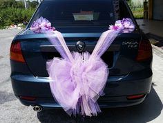 the back end of a car decorated with purple tulle and bow tie decorations,