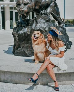 a woman sitting next to a dog in front of a statue