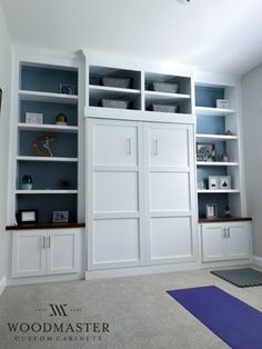 an empty room with white bookcases and yoga mat on the floor in front of it