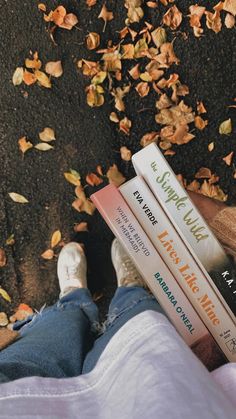 a person laying on the ground with their legs crossed and holding three books in front of them