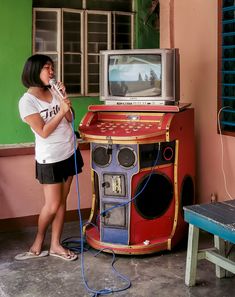 a woman standing in front of an old fashioned jukebox and holding a microphone