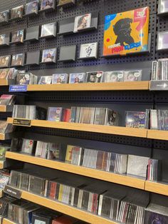 a woman is looking at cd's on the shelves in a store, and she is pointing to them with her finger