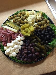 a platter with olives, pickles, cheese and other foods on it