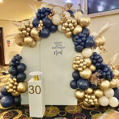 a birthday arch made out of balloons and other decorations on display in a lobby area