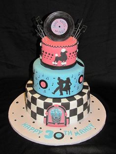 a three tiered cake with music themed designs on it's sides and an alarm clock on top