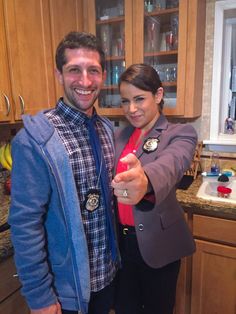 a man and woman are standing in the kitchen posing for a photo with badges on their jackets