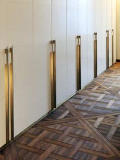 an empty hallway with white cabinets and wood flooring on the side, along with gold handles