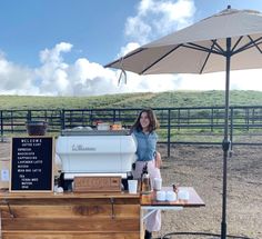 a woman standing behind a counter with an ice cream cart in front of her on a farm