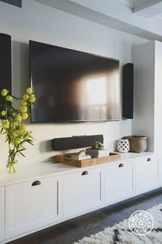 a large flat screen tv mounted to the side of a wall above a white entertainment center