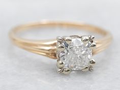 an engagement ring with a cushion cut diamond in the center, on a white surface