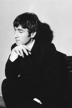 a black and white photo of a young man in a suit sitting on a chair