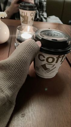 a person holding a coffee cup on top of a wooden table