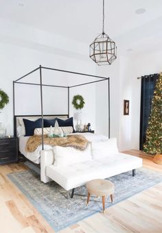 a white bed sitting on top of a wooden floor next to a living room filled with furniture