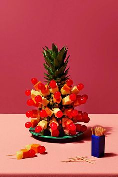 a pineapple and cherries are arranged on a plate