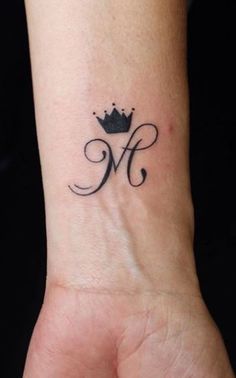 a woman's wrist with a crown tattoo on her left hand and the letter m in the middle