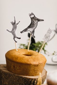 a cake with two cats on top of it and some sticks sticking out of the icing