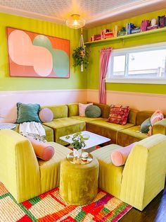 a living room filled with yellow couches and colorful rugs