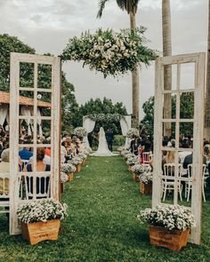 an outdoor ceremony with white chairs and flowers on the aisle, surrounded by palm trees