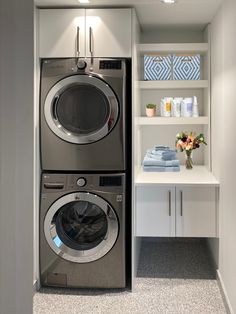 a washer and dryer in a room with white shelves on the wall behind them