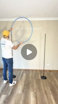 a man holding a large blue hula hoop on top of a hard wood floor