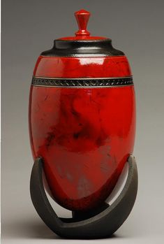 a red vase sitting on top of a metal stand