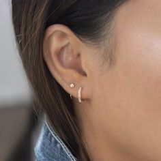 a close up of a woman's ear wearing gold earrings with diamonds on them