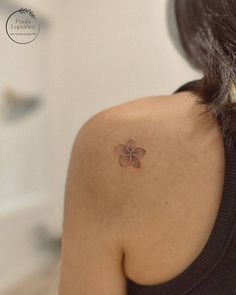 the back of a woman's shoulder with a small flower tattoo on her left arm