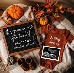 a baby announcement is displayed on a blanket next to pumpkins and other fall decorations