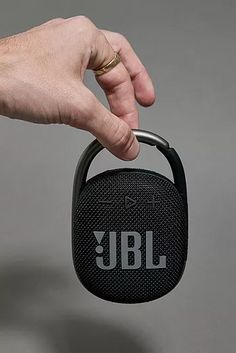 a hand holding a jbl mini speaker with the word jbl written on it