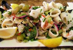 a white plate topped with pasta salad and lemon wedges