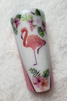 a pink flamingo with flowers painted on it's side sitting on a white furnishing